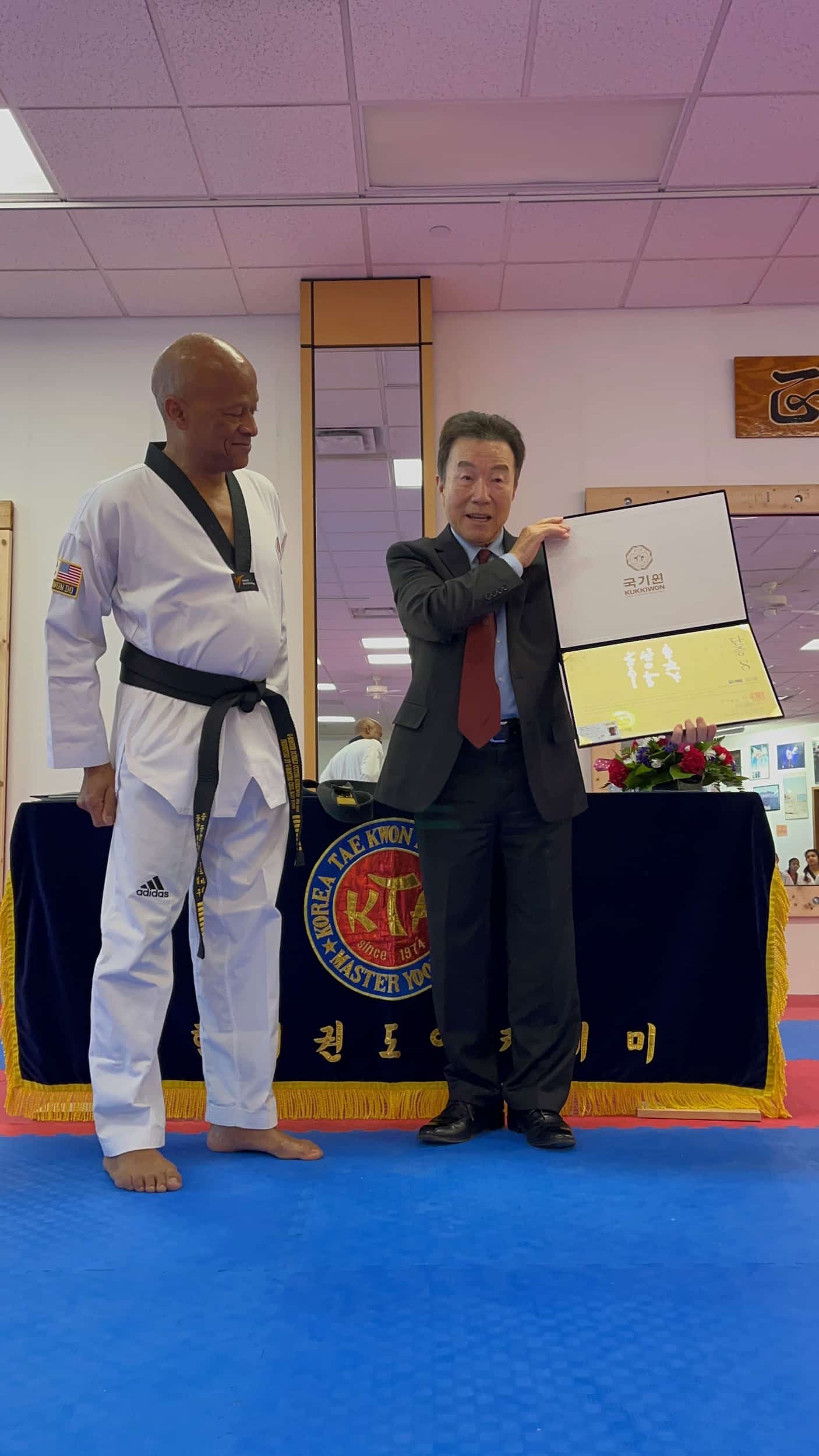 Korean Tae Kwon Do owners holding up a certificate on the mat